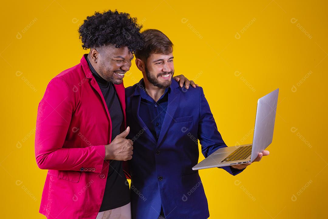 Dois empresários com laptop nas mãos comemorando vendas online.