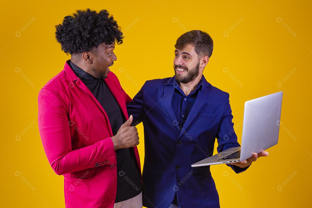 Dois empresários com laptop nas mãos comemorando vendas online.