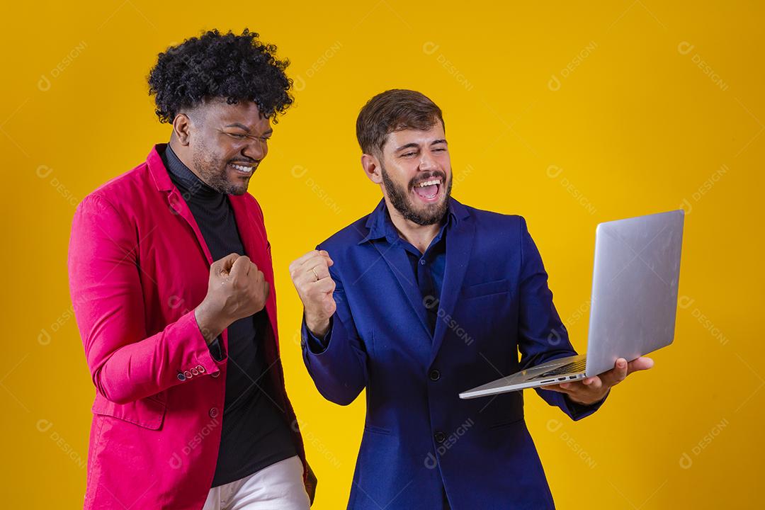 Dois empresários com laptop nas mãos comemorando vendas online.
