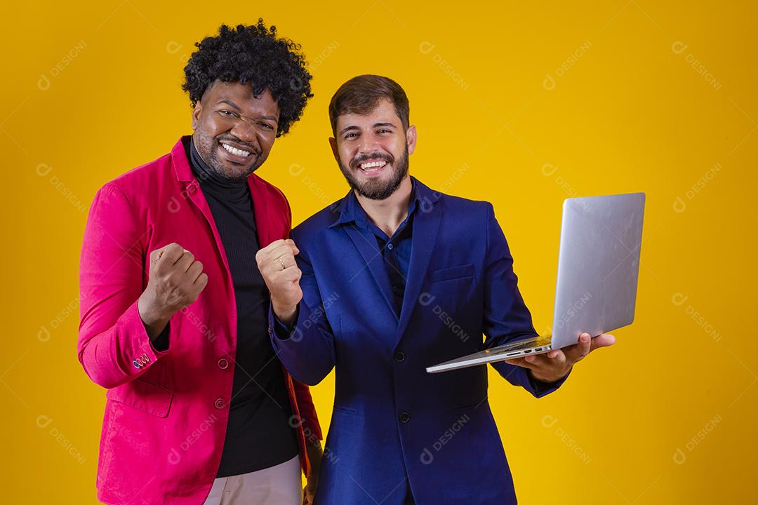 Dois empresários com laptop nas mãos comemorando vendas online.