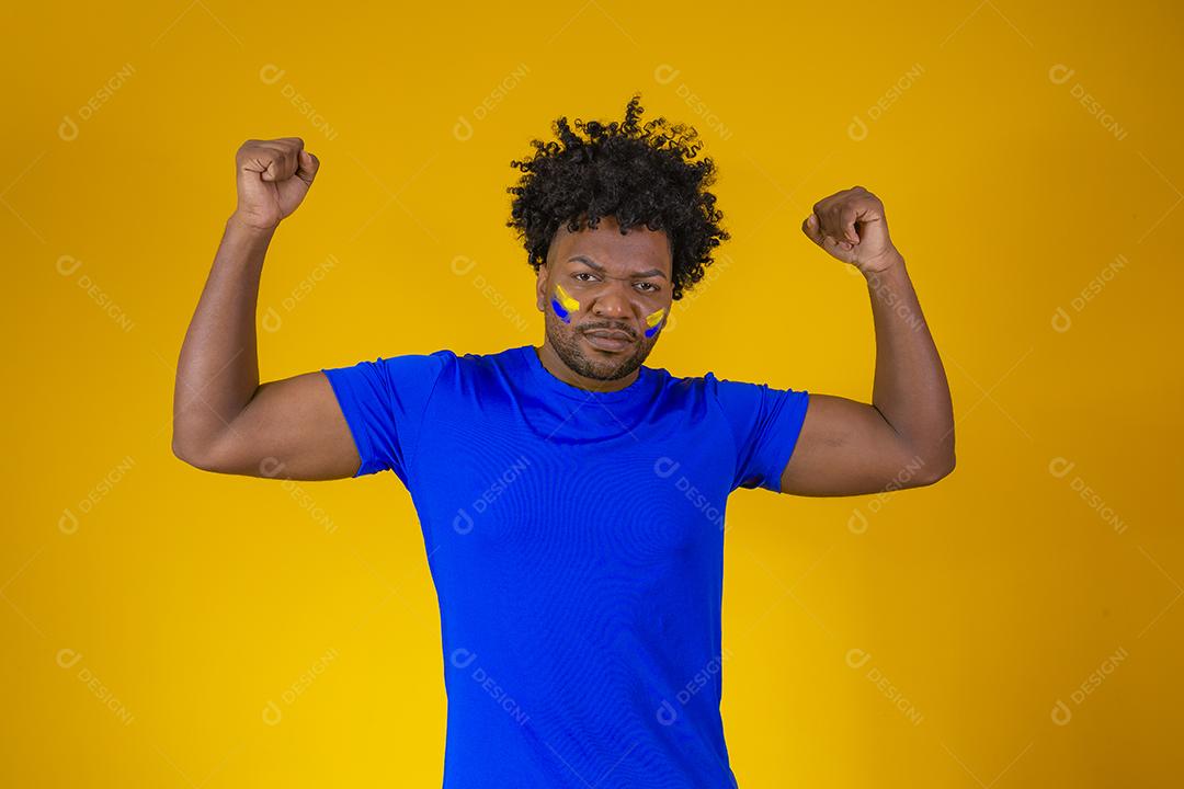 menino afro bonito comemorando a vitória. Homem afro com rosto pintado comemorando em fundo amarelo