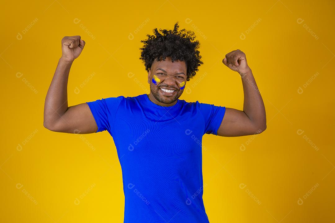 menino afro bonito comemorando a vitória. Homem afro com rosto pintado comemorando em fundo amarelo