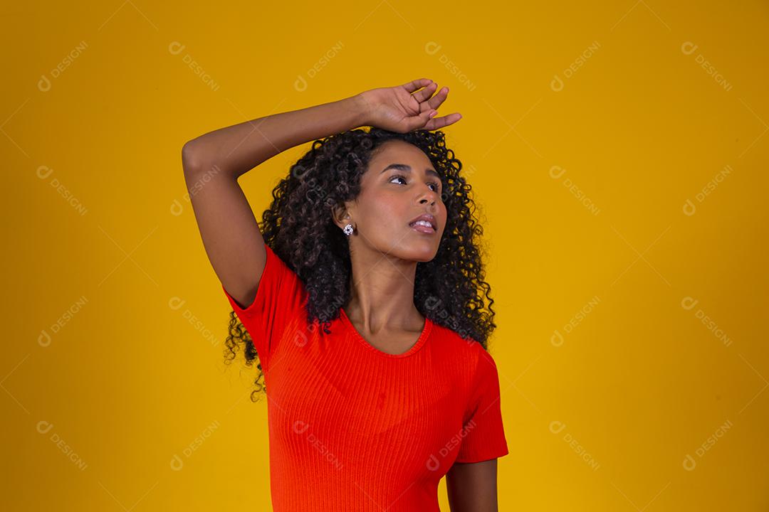 Jovem afro com cabelo encaracolado sorrindo para a câmera em fundo amarelo