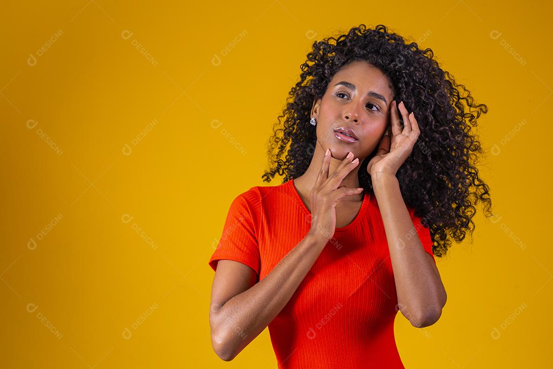 Jovem afro com cabelo encaracolado sorrindo para a câmera em fundo amarelo