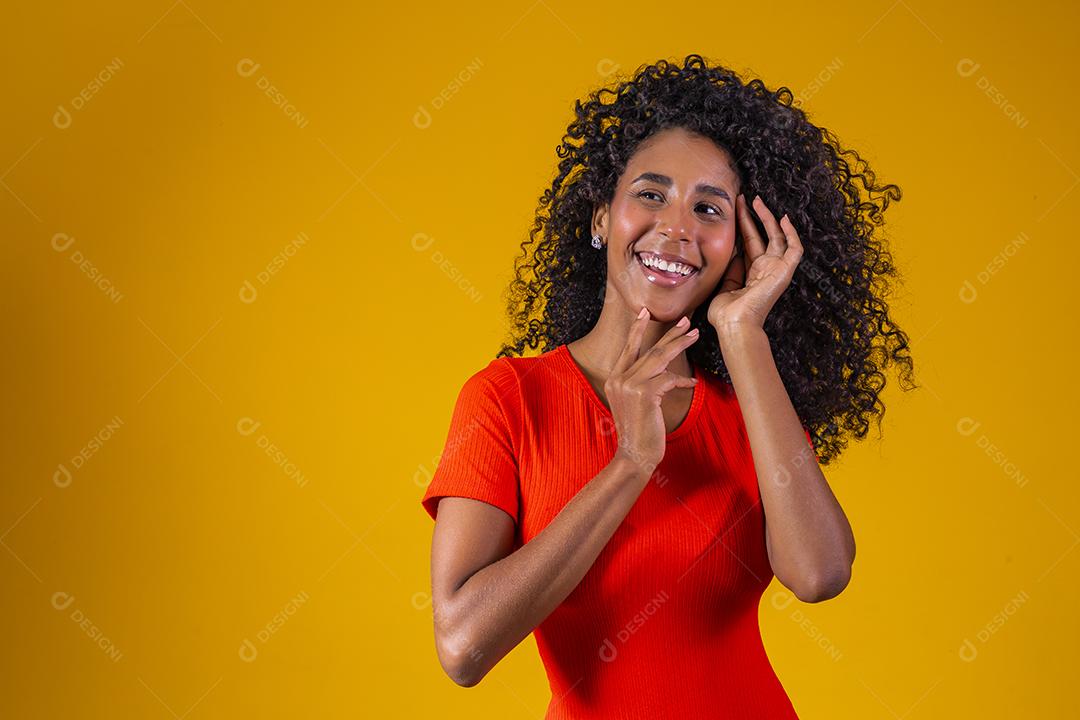 Jovem afro com cabelo encaracolado sorrindo para a câmera em fundo amarelo