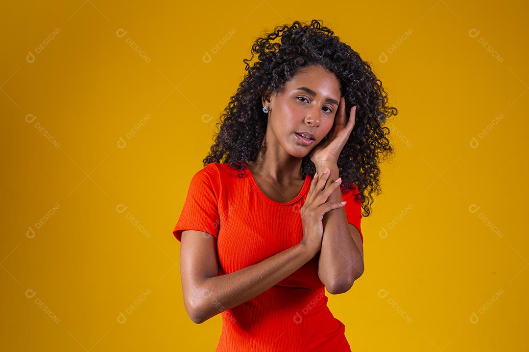 Jovem afro com cabelo encaracolado sorrindo para a câmera em fundo amarelo