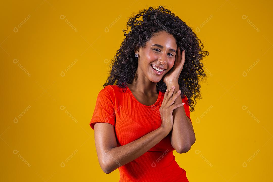 Jovem afro com cabelo encaracolado sorrindo para a câmera em fundo amarelo