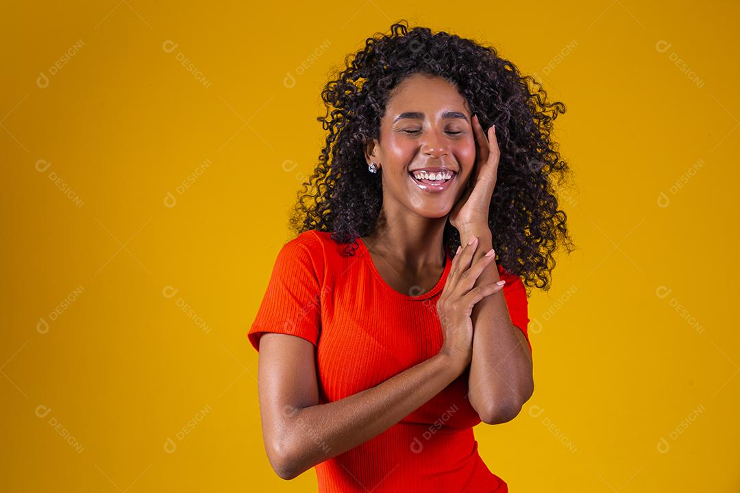 Jovem afro com cabelo encaracolado sorrindo para a câmera em fundo amarelo
