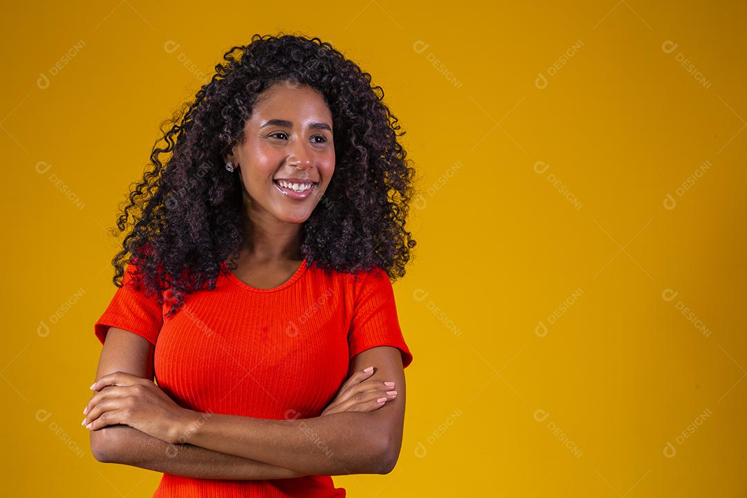 Jovem afro com cabelo encaracolado sorrindo para a câmera em fundo amarelo