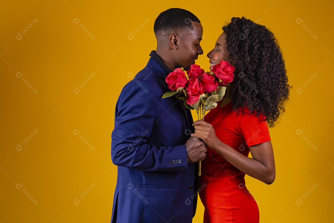 Lindo casal elegante está se beijando atrás de rosas, em fundo amarelo