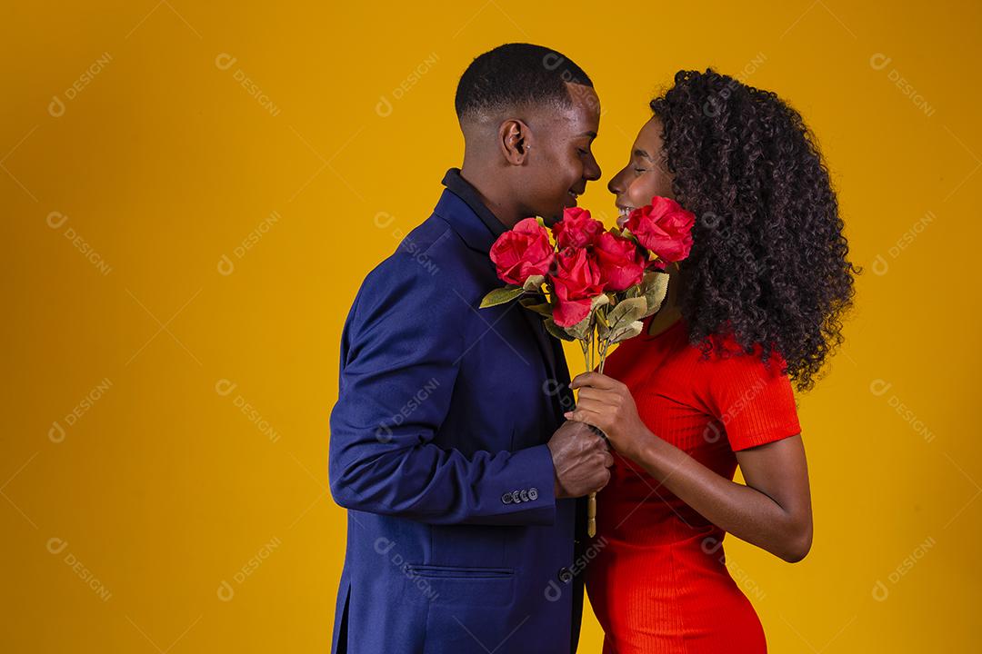 Lindo casal elegante está se beijando atrás de rosas, em fundo amarelo