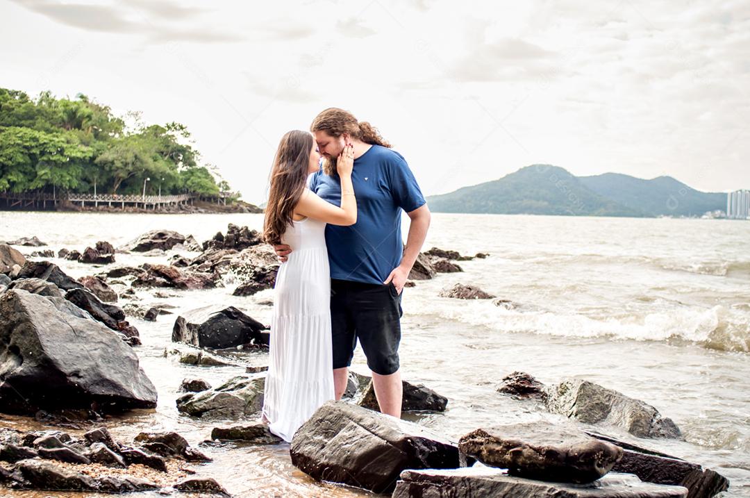 Um casal apaixonado nas rochas à beira-mar.