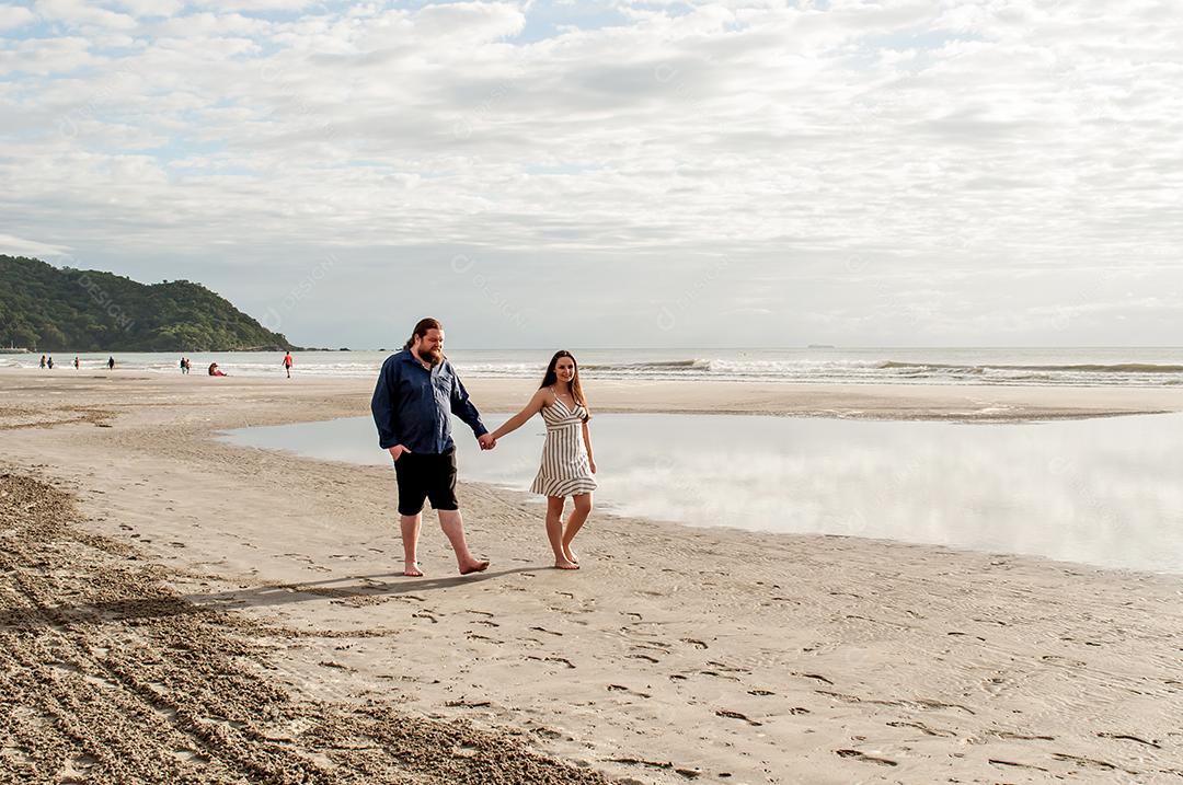 Casal apaixonado andando na praia pela manhã