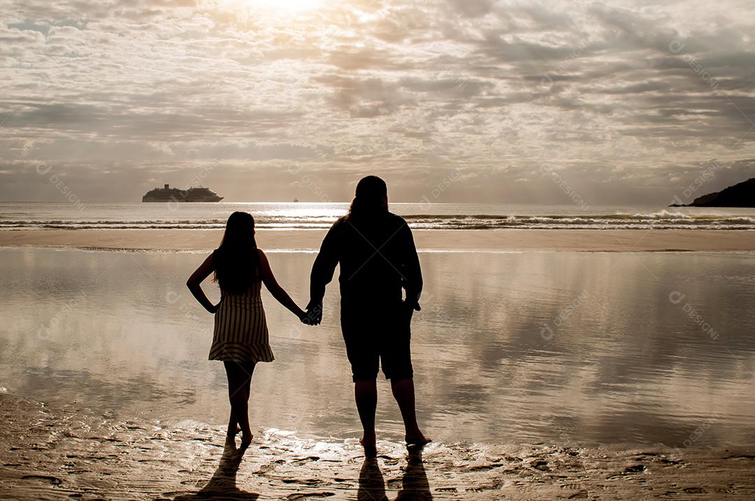 Silhueta de casal apaixonado na praia ao nascer do sol