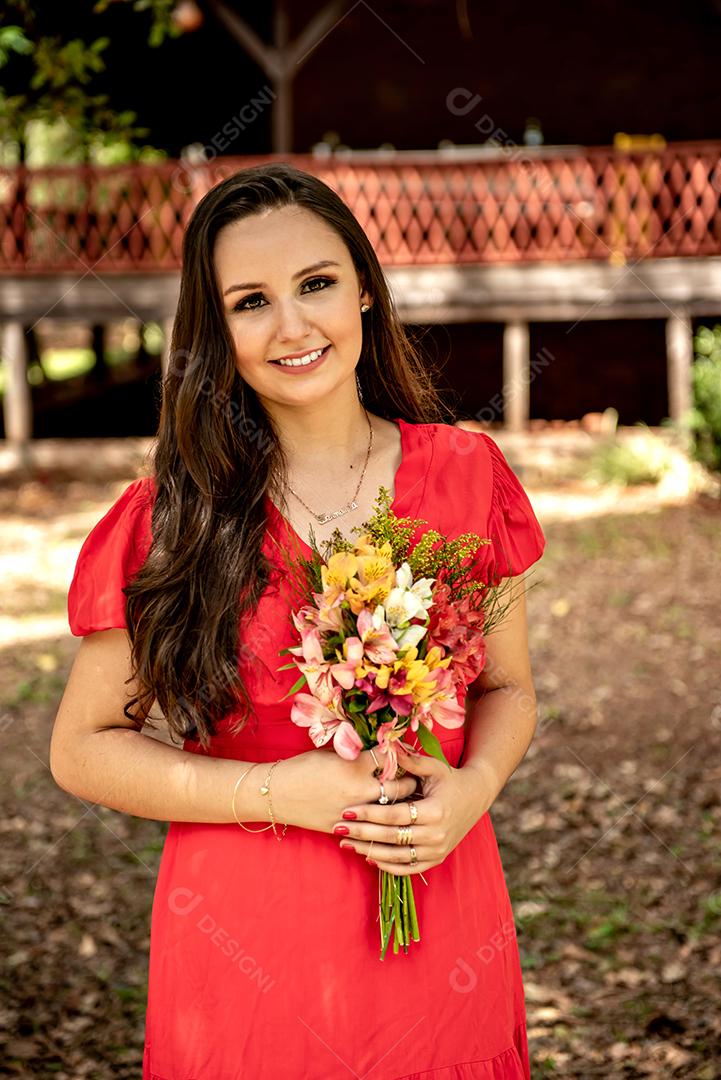 Mulher feliz em um vestido vermelho segurando um buquê de flores