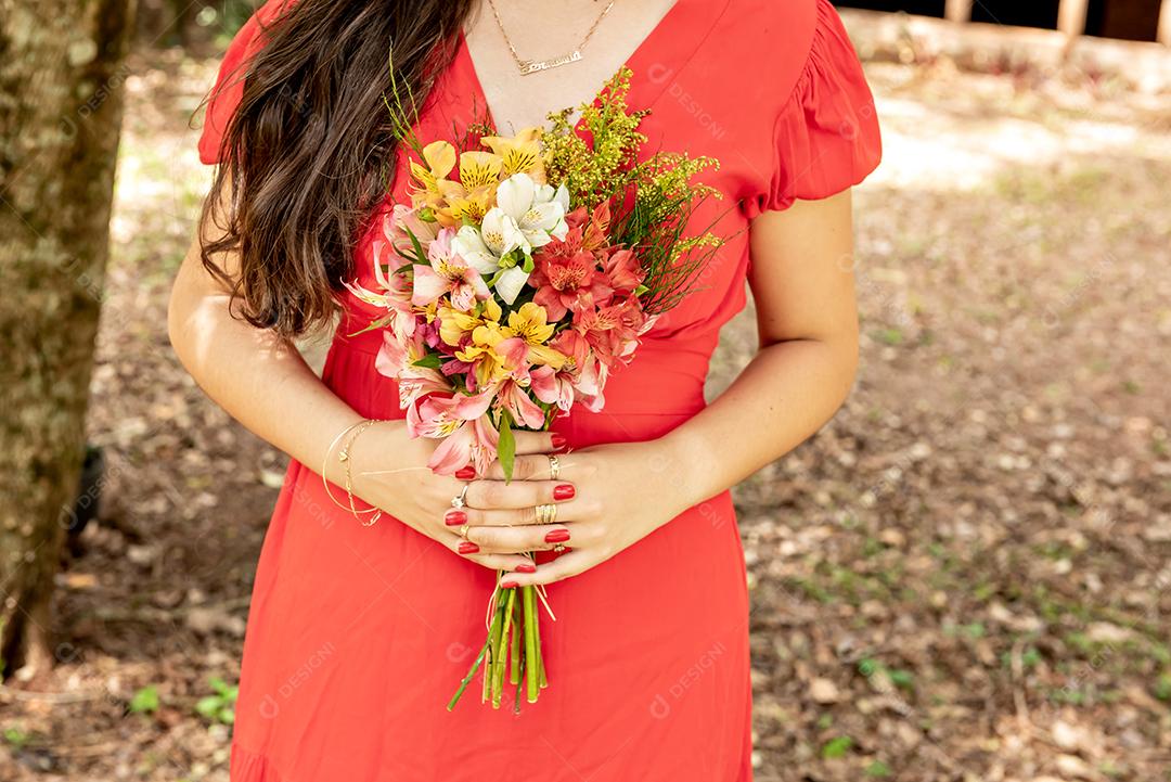 Mulher de vestido vermelho segurando um buquê de flores