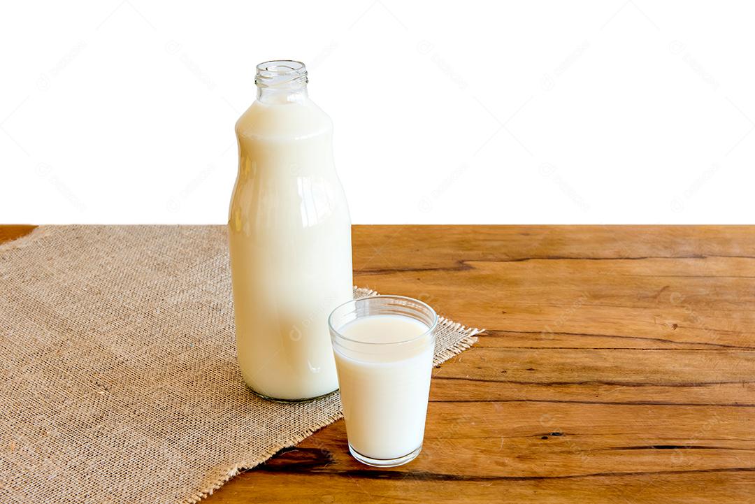 garrafa e copo de leite na mesa de madeira com fundo branco
