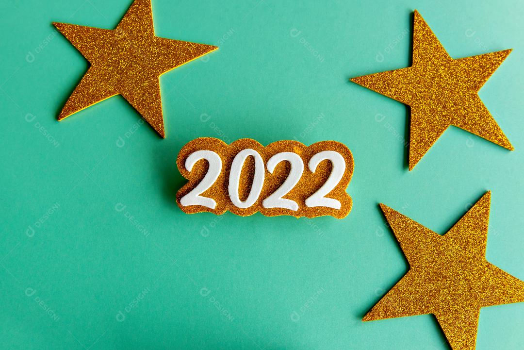 Fundo verde com papel EVA ano 2022 dourado e algumas estrelas feliz ano novo