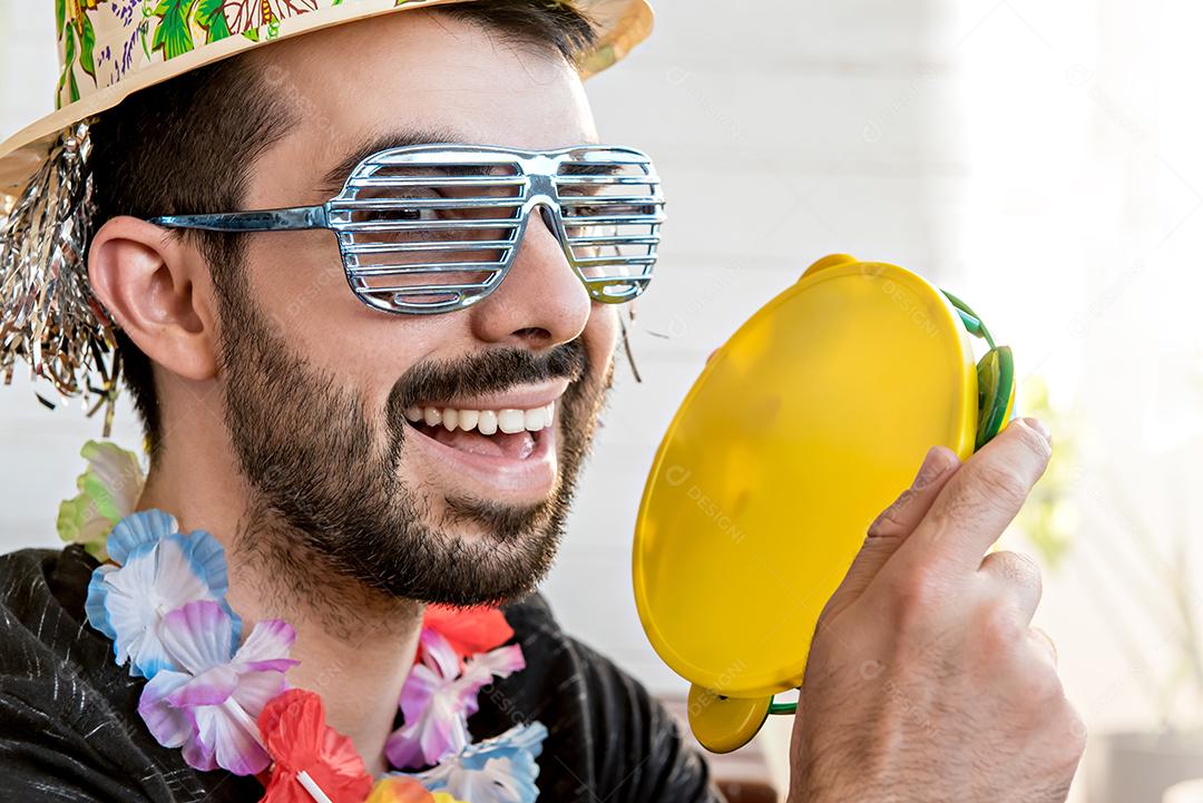 Jovem vestido com fantasia de carnaval tocando pandeiro na festa de carnaval