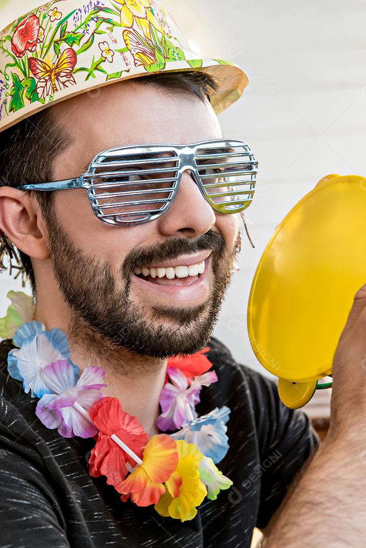 Jovem vestido com fantasia de carnaval tocando pandeiro na festa de carnaval