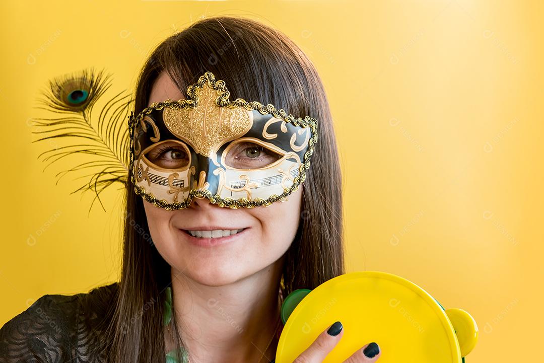 Jovem vestida com fantasia de carnaval tocando pandeiro na festa de carnaval, fundo amarelo