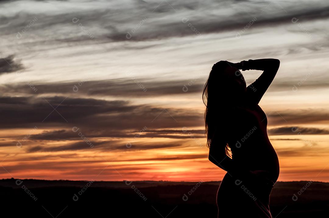 Silhueta grávida ao pôr do sol.