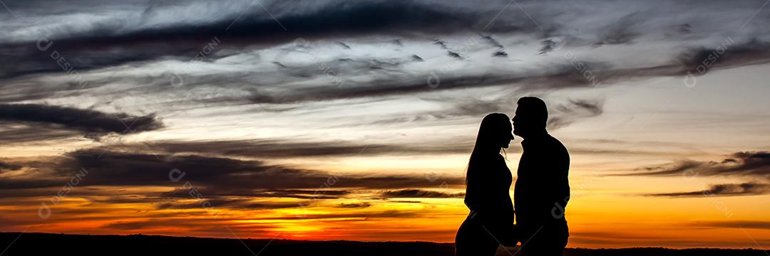 Silhueta de casal apaixonado no formato ao ar livre do pôr do sol.