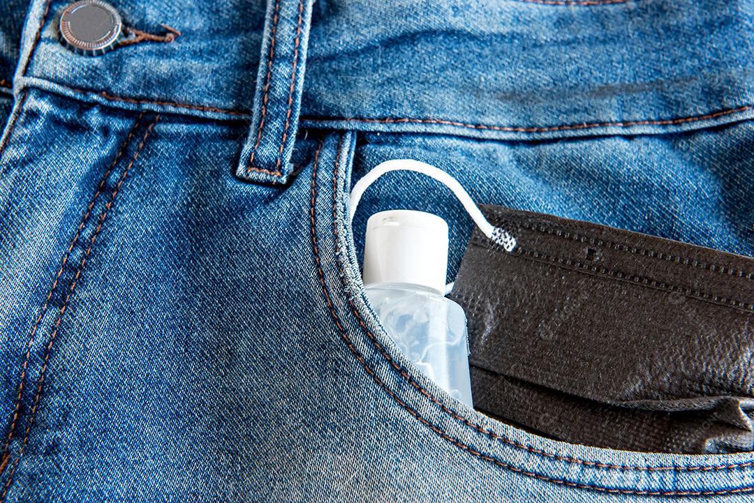 Máscara e álcool gel no bolso da calça jeans, prevenção ao COVID-19.