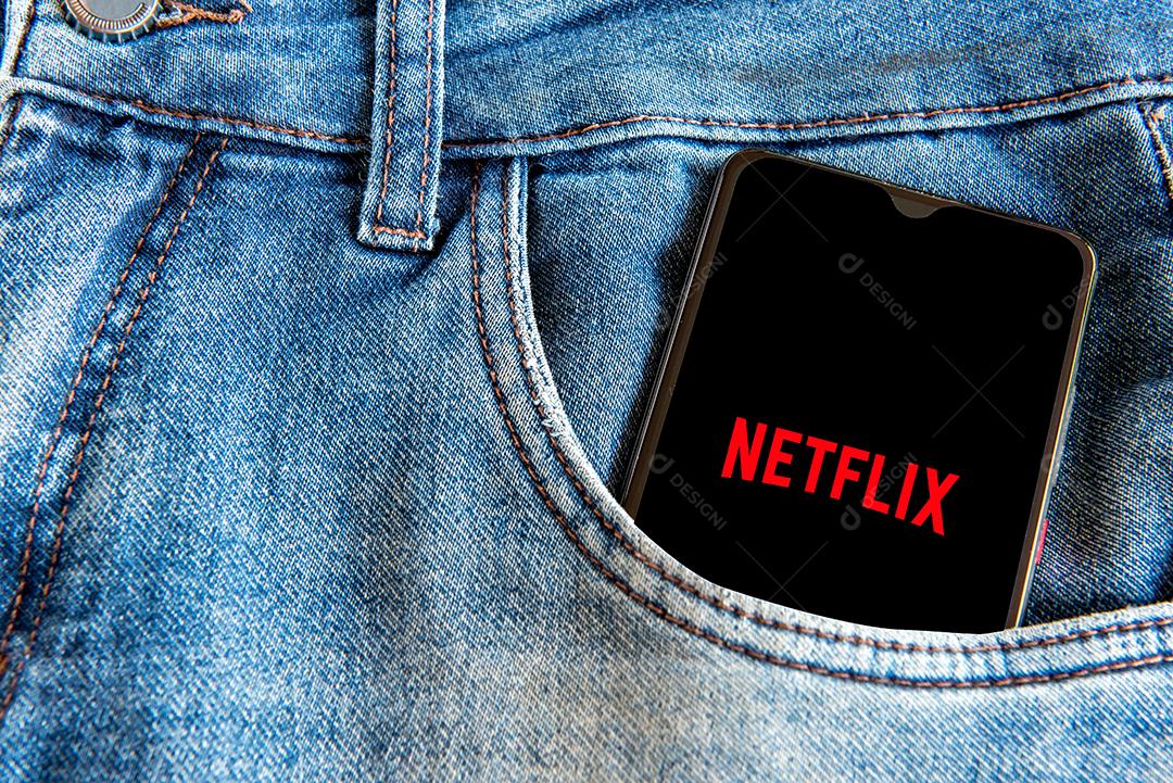 Calça jeans com celular com tela aberta de Netflix  no bolso