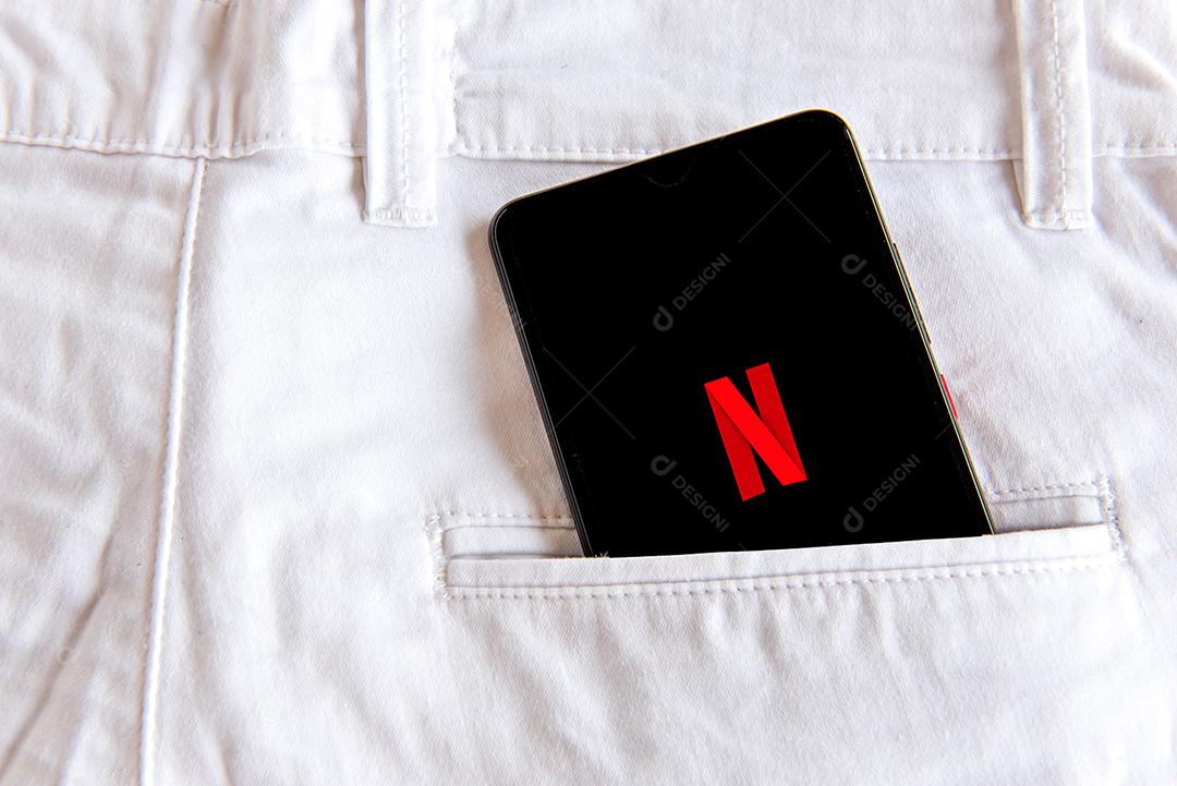 Calça jeans com celular com tela aberta de Netflix no bolso