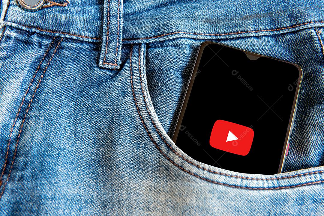 Calça jeans com celular com tela aberta de Youtube no bolso