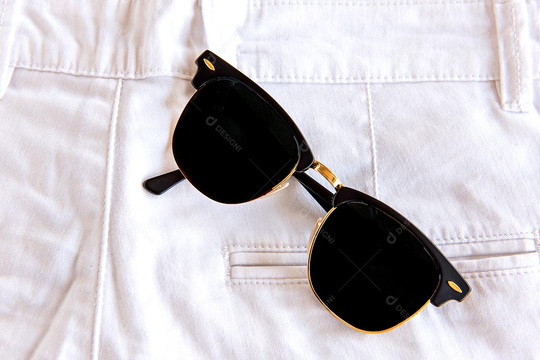 óculos de sol no bolso da calça branca.