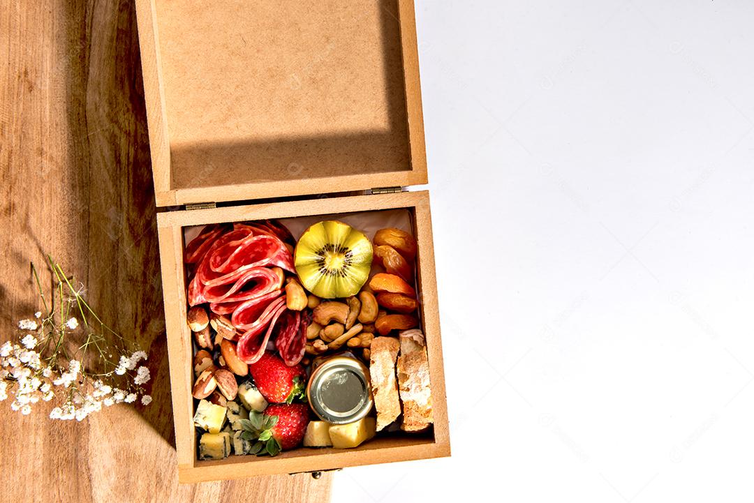 Caixa com comida. Salame, queijo, pão, nozes e kiwi