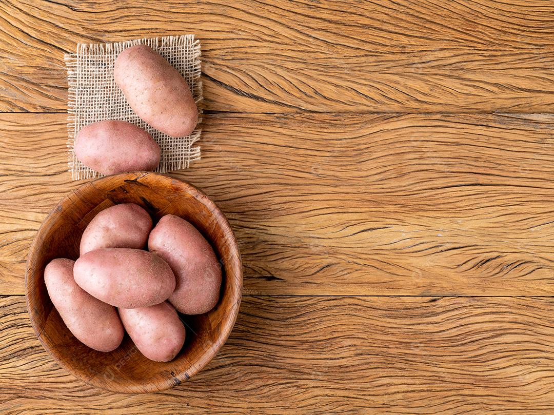 Batata vermelha em uma cesta sobre mesa de madeira com espaço de cópia
