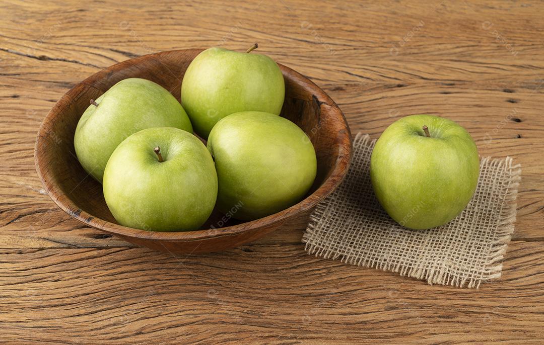 Maçãs verdes em uma tigela sobre a mesa de madeira