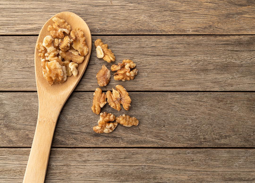 Nozes em uma colher sobre mesa de madeira com espaço de cópia