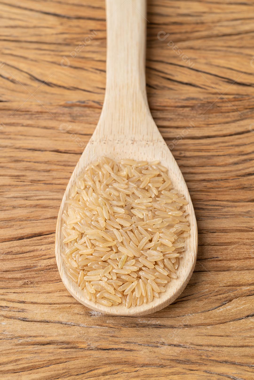Arroz integral cru em uma colher sobre a mesa de madeira