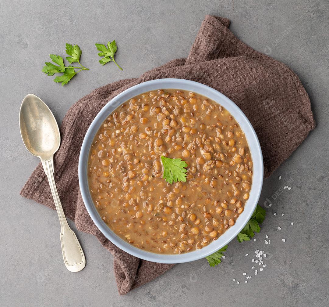 Sopa de lentilha em uma tigela com tempero sobre fundo de pedra