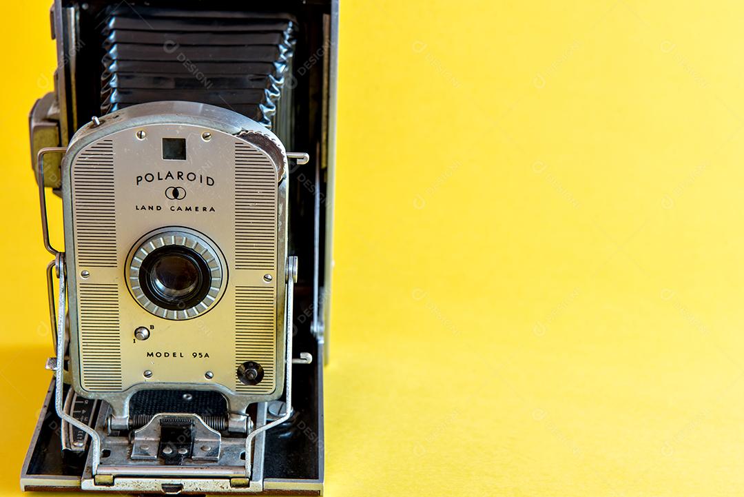 Câmera fotográfica Polaroid velha e retrô em fundo amarelo.
