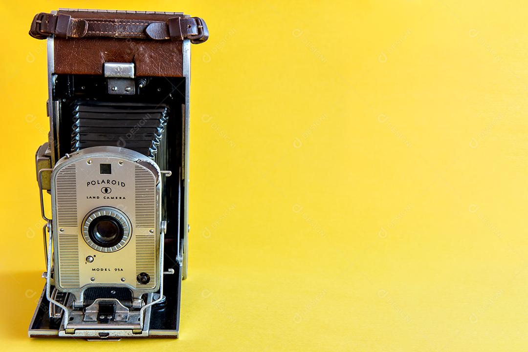Câmera fotográfica Polaroid velha e retrô em fundo amarelo.
