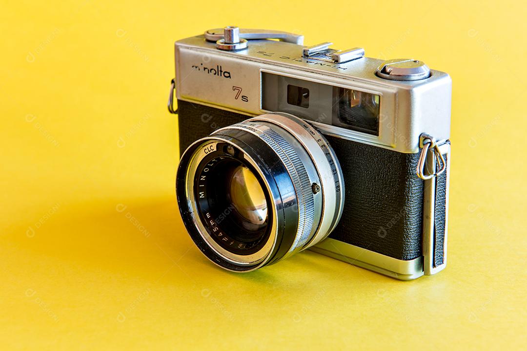 Câmera fotográfica antiga e vintage Minolta em fundo amarelo.