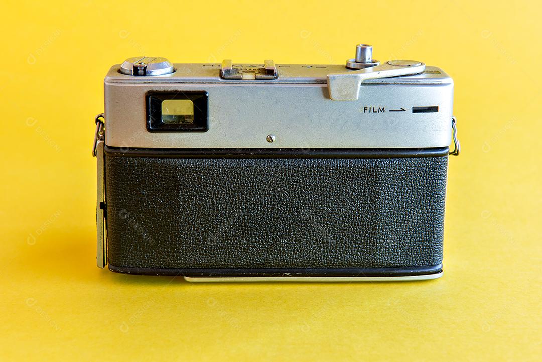 Câmera fotográfica antiga e vintage Minolta em fundo amarelo.