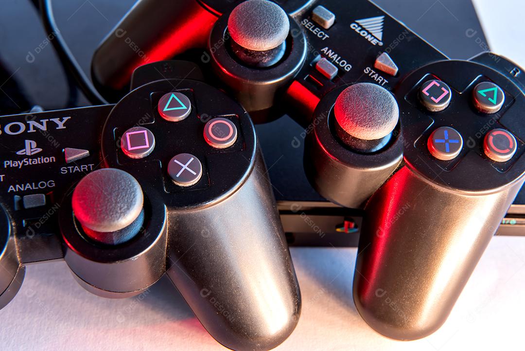 Consoles de videogame antigos em fundo branco com luzes vermelhas.