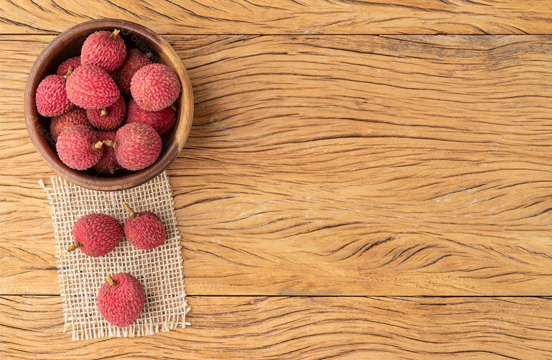 Lichias em uma tigela sobre mesa de madeira com espaço de cópia