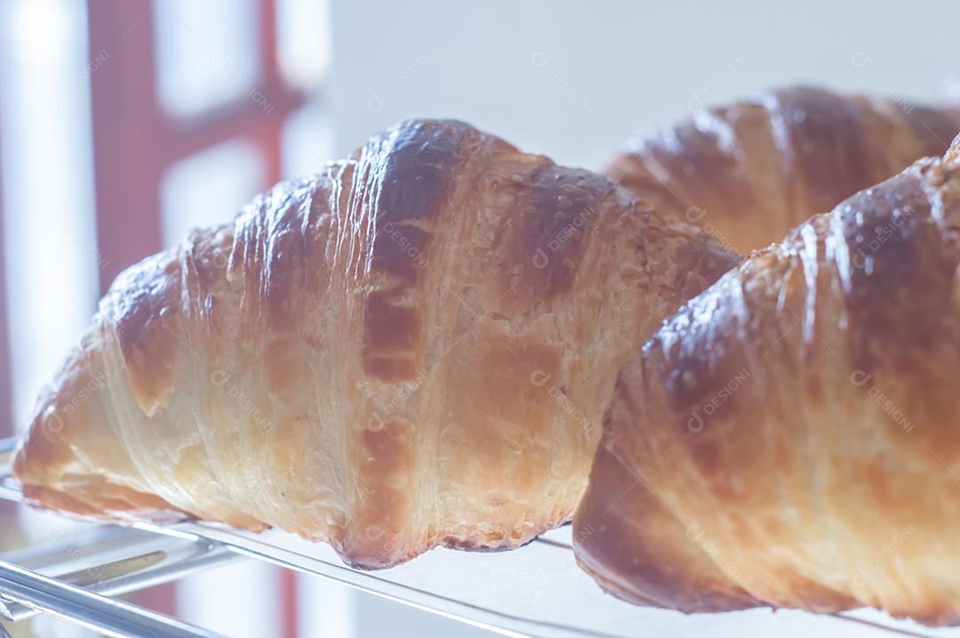 Croissant francês recentemente apoiado brilhante nos raios do sol da manhã, luz natural.