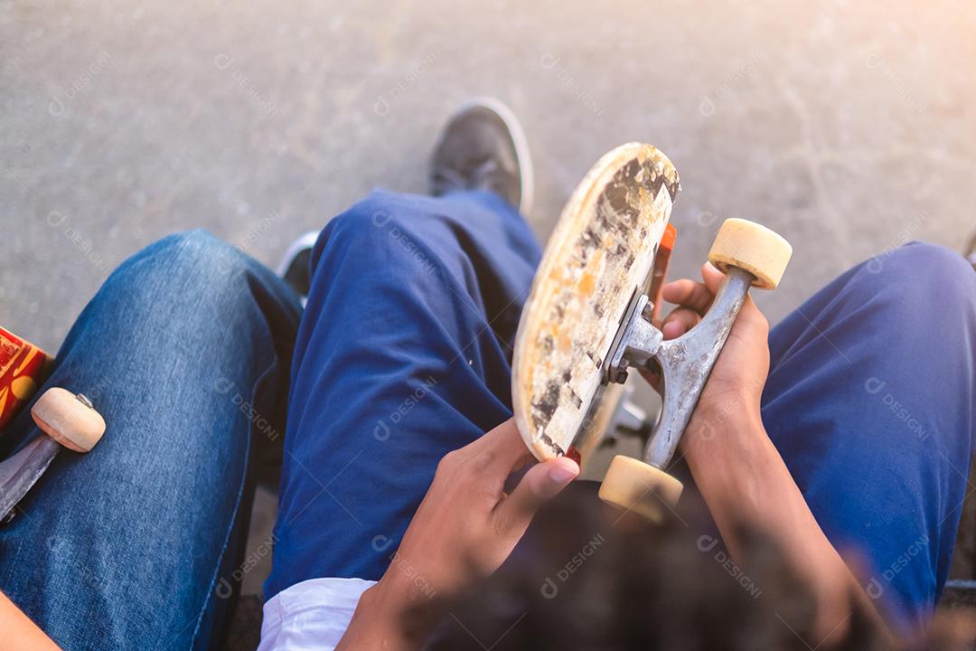 jovens skatistas adolescentes sentados juntos em um parque de skate com skates na mão esporte radical, amizade