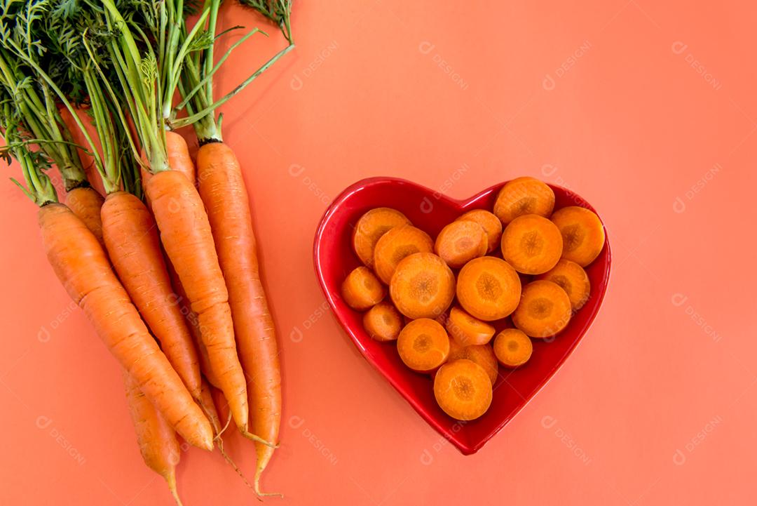 Fatias de cenoura e tiras em uma mesa com fundo laranja.