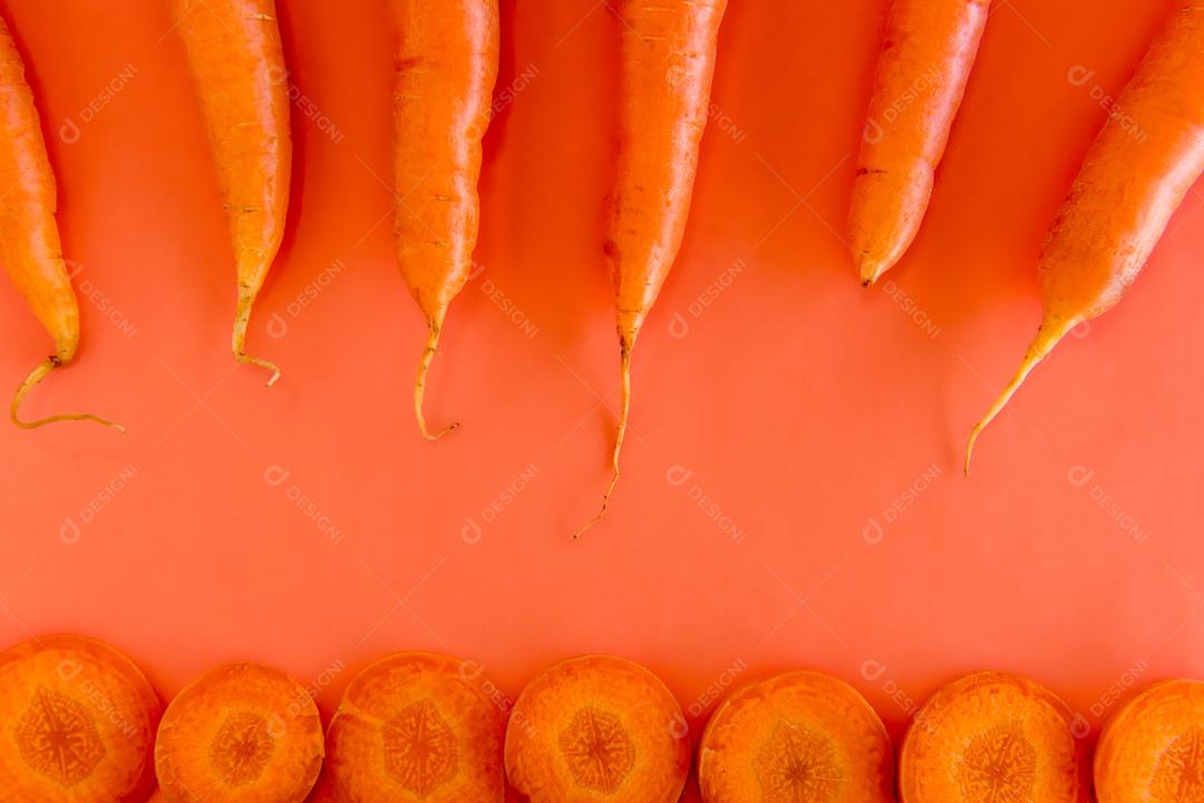 Fatias de cenoura em fundo laranja.