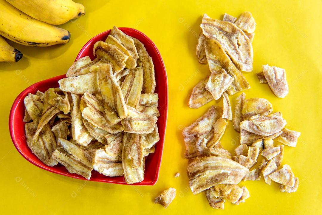 Servindo de chips de banana salgada em fundo amarelo.