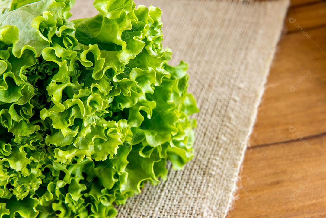 Salada, alface e espinafre em uma mesa de madeira.